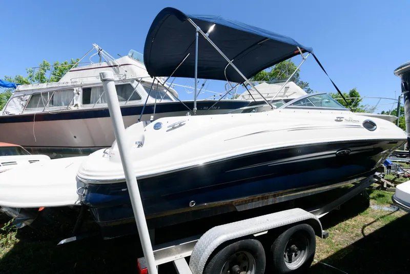 The Image of 2009 Sea Ray 240 Sundeck boat on trailer with canopy, parked outdoors. - 0