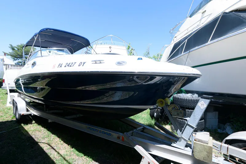 Slide: The Image of 2009 Sea Ray 240 Sundeck boat on trailer, parked outdoors under clear blue sky. - 1