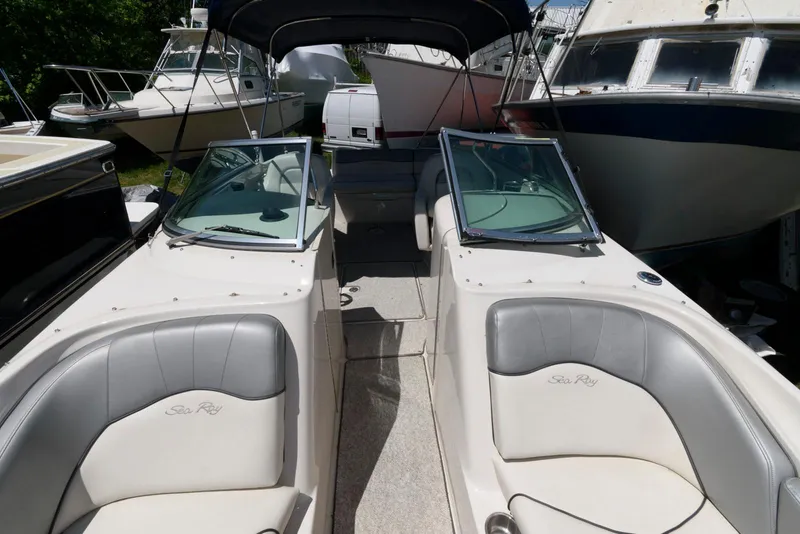 Slide: The Image of 2009 Sea Ray 240 Sundeck boat interior with seating and windshield, docked among other boats. - 5