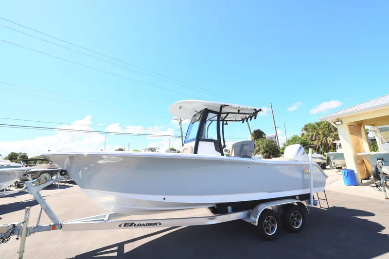 Slide: The Image of 2025 Sea Hunt Ultra 239 SE boat on trailer under clear blue sky. - 7