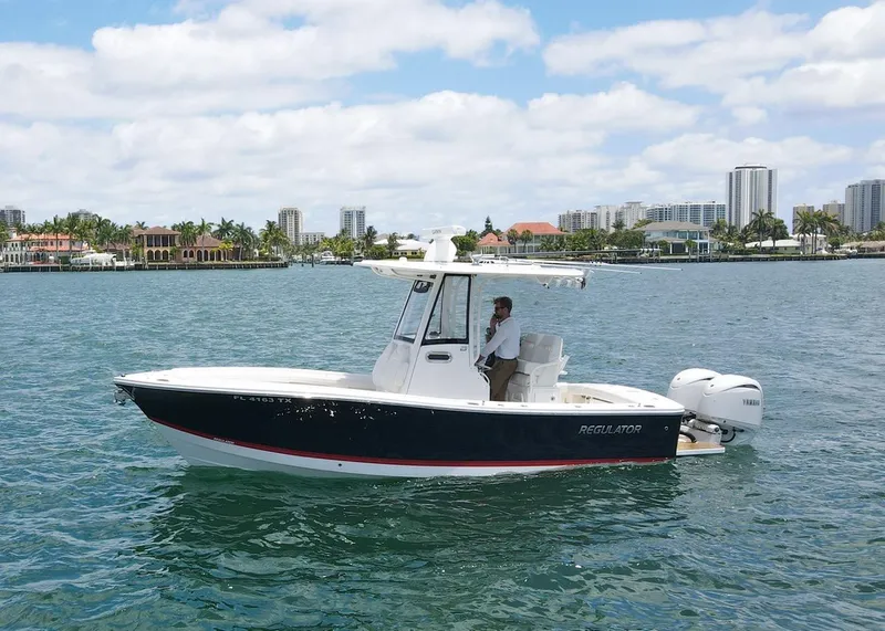 Slide: The Image of 2024 Regulator 23 boat on water, city skyline in background, clear sky. - 1