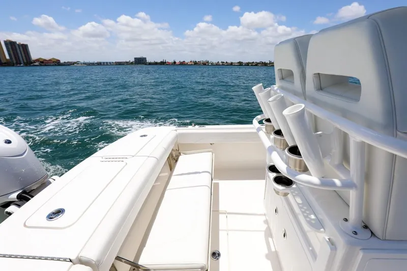 Slide: The Image of 2024 Regulator 23 boat interior with seating and rod holders, overlooking a scenic ocean view. - 16