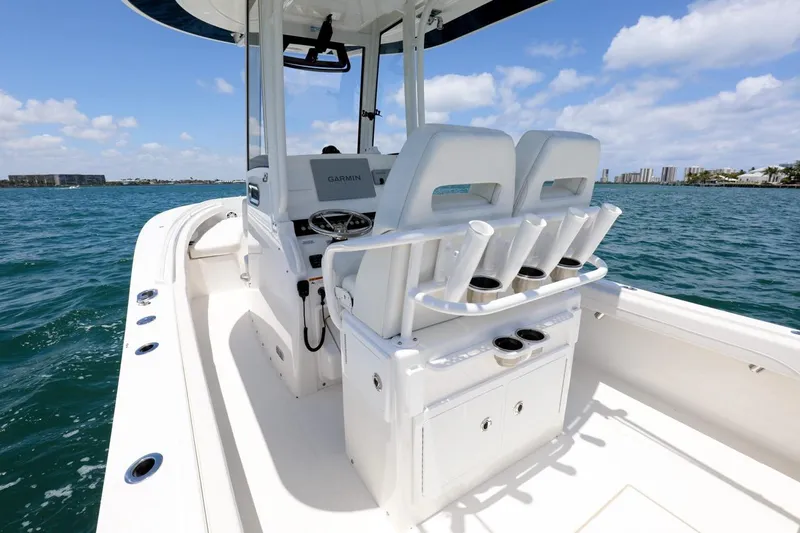 Slide: The Image of 2024 Regulator 23 boat interior with dual seats and rod holders on a sunny day. - 19