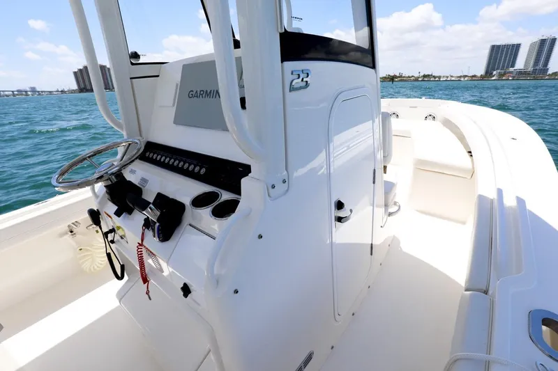 Slide: The Image of 2024 Regulator 23 boat interior with Garmin system, steering wheel, and ocean backdrop. - 28
