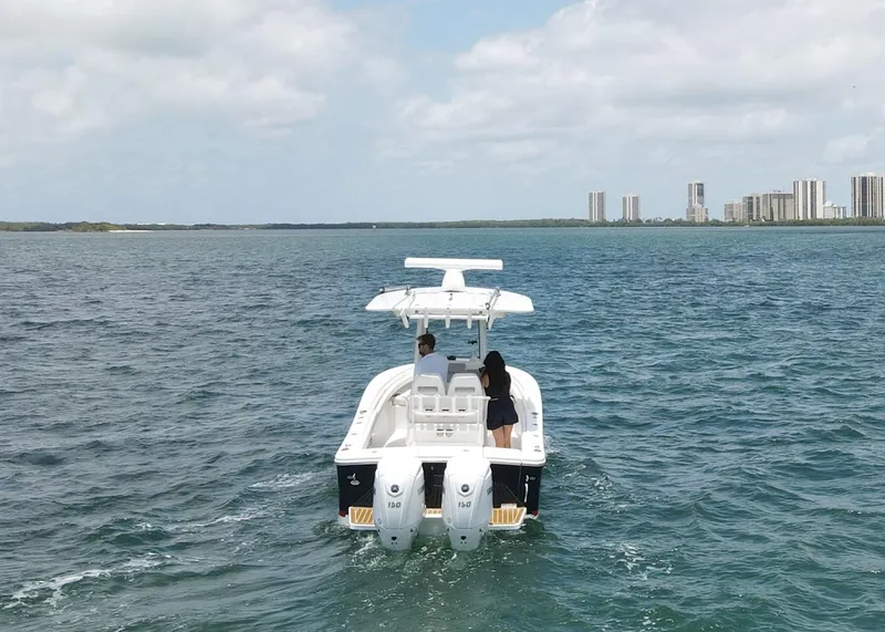 Slide: The Image of 2024 Regulator 23 boat cruising on open water with city skyline in background. - 32