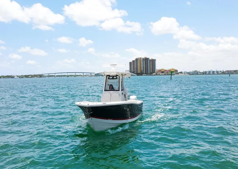 Slide: The Image of 2024 Regulator 23 boat cruising on open water with cityscape in background. - 34