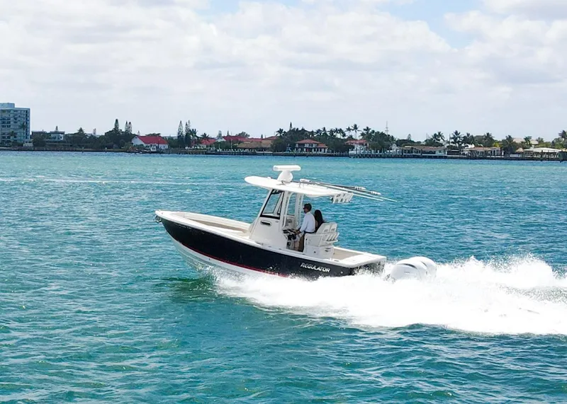 Slide: The Image of 2024 Regulator 23 boat cruising on blue water near a coastal town. - 35