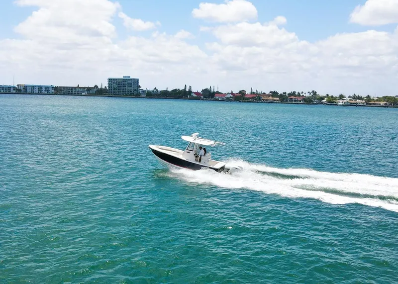Slide: The Image of 2024 Regulator 23 boat cruising on blue water under a partly cloudy sky. - 36