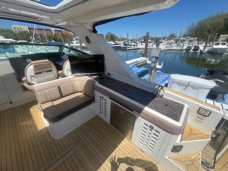 Slide: The Image of 2018 Sea Ray SLX 400 boat interior with seating, kitchenette, and marina view. - 3