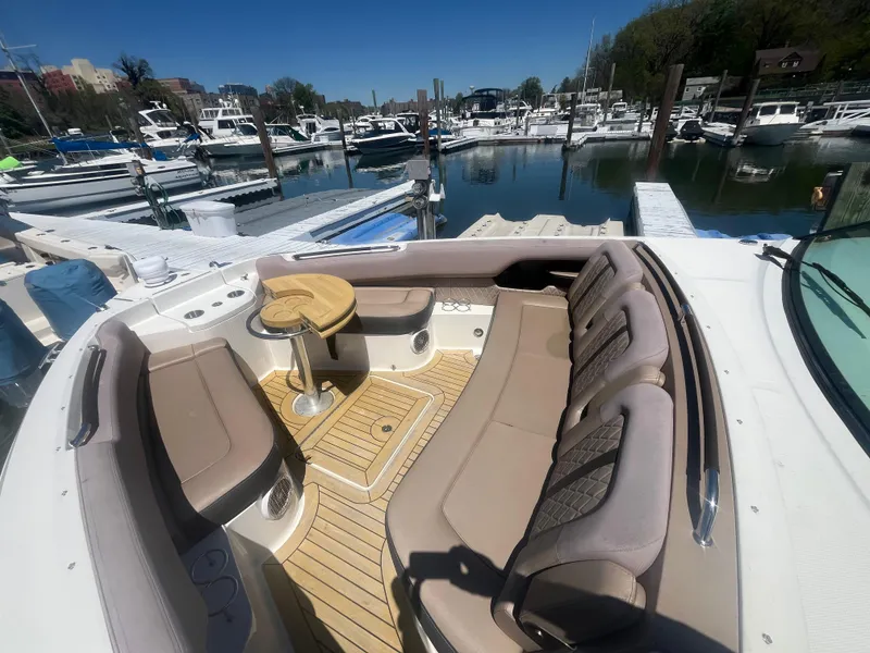 Slide: The Image of 2018 Sea Ray SLX 400 boat interior with beige seating at a marina. - 6