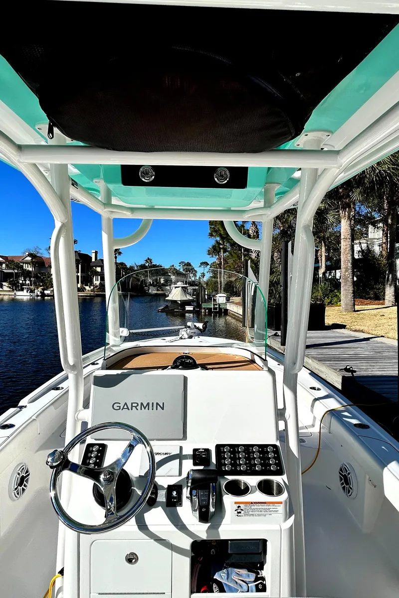 Slide: The Image of 2021 Caymas 28 HB boat cockpit with Garmin navigation, docked by a scenic waterfront. - 21