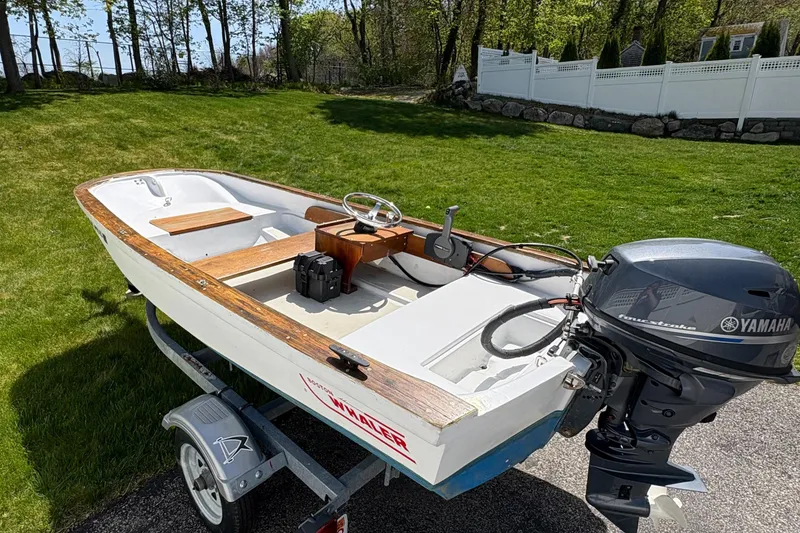 Slide: The Image of 1984 Boston Whaler 11 boat with Yamaha outboard motor on a trailer, parked on grass. - 3