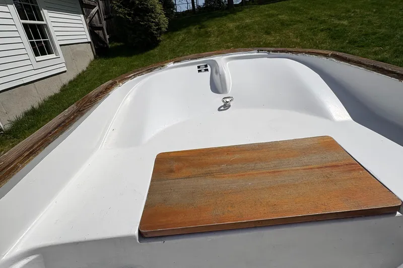 Slide: The Image of 1984 Boston Whaler 11 boat, white interior, wooden seat, grassy background. - 8