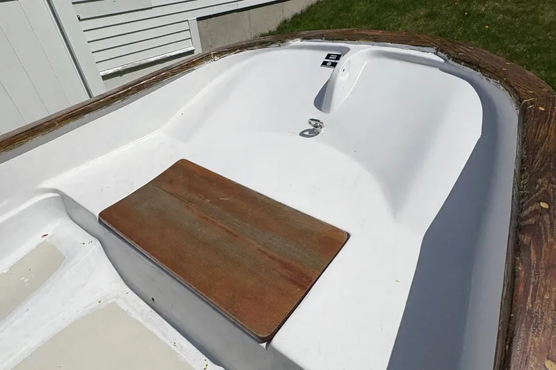 Slide: The Image of 1984 Boston Whaler 11 boat interior with wooden seat, white hull, and outdoor setting. - 9