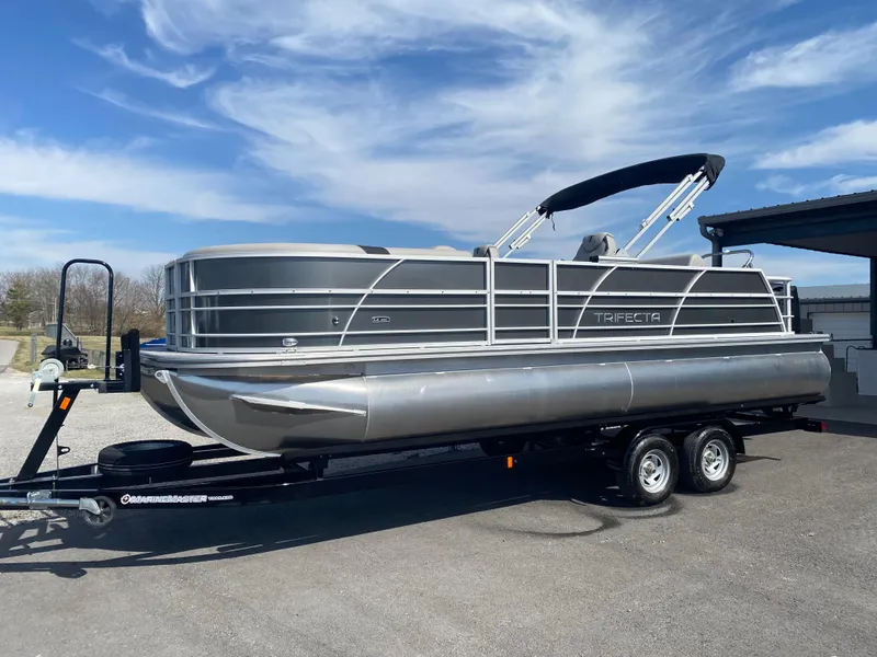 Slide: The Image of 2025 Trifecta LE Series 22UL pontoon boat on trailer under blue sky. - 2