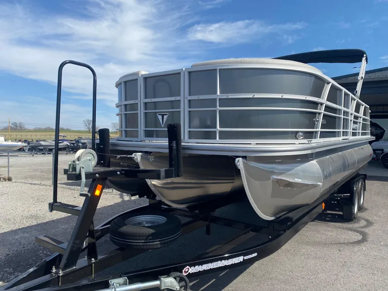 Slide: The Image of 2025 Trifecta LE Series 22UL pontoon boat on trailer, parked outdoors under blue sky. - 6