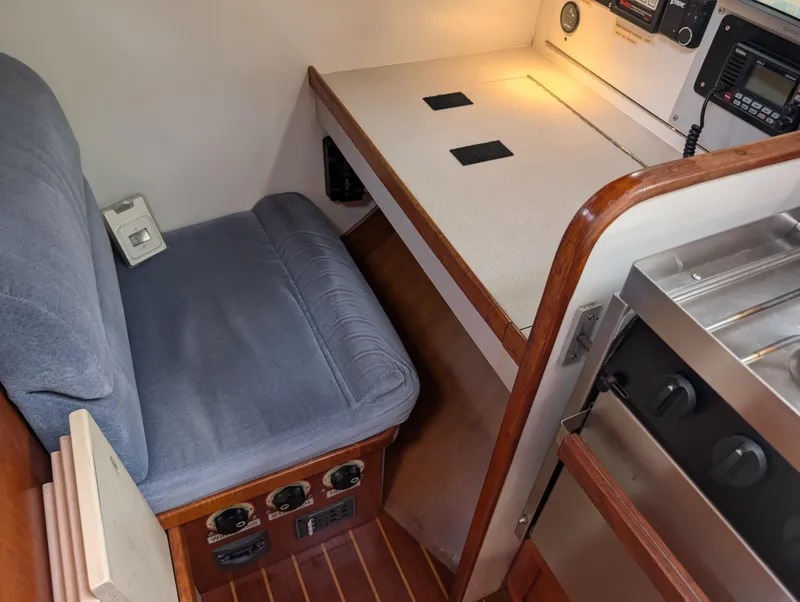Slide: The Image of Cozy navigation station in 1998 Caliber 40 LRC yacht with cushioned seat and control panels. - 21