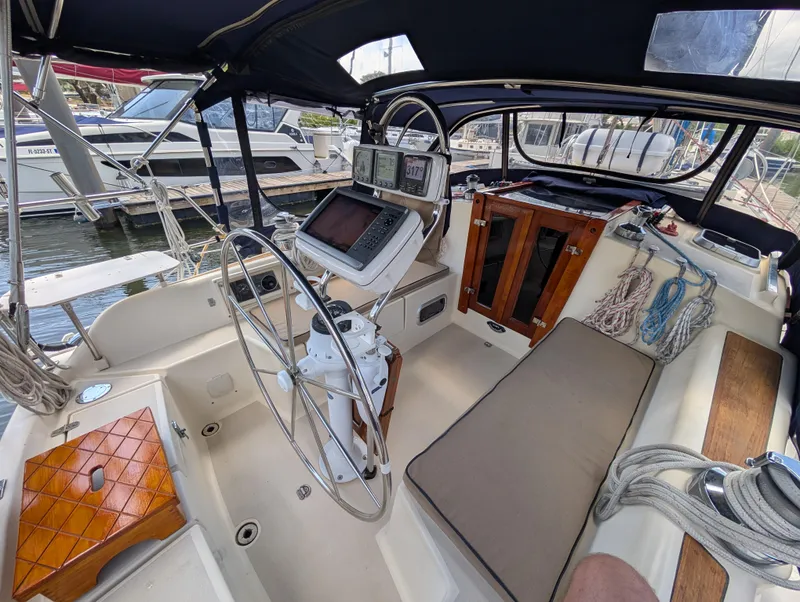 Slide: The Image of 1998 Caliber 40 LRC sailboat cockpit with steering wheel, navigation equipment, and seating at marina. - 34