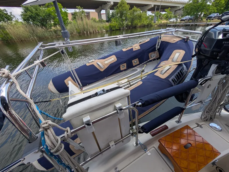 Slide: The Image of Sailboat deck with inflatable dinghy, Caliber 40 LRC, 1998 model, docked by a river. - 37