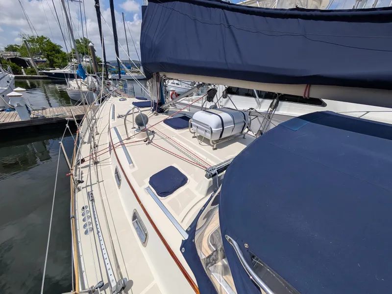 Slide: The Image of 1998 Caliber 40 LRC sailboat docked, featuring blue canvas covers and a spacious deck layout. - 43