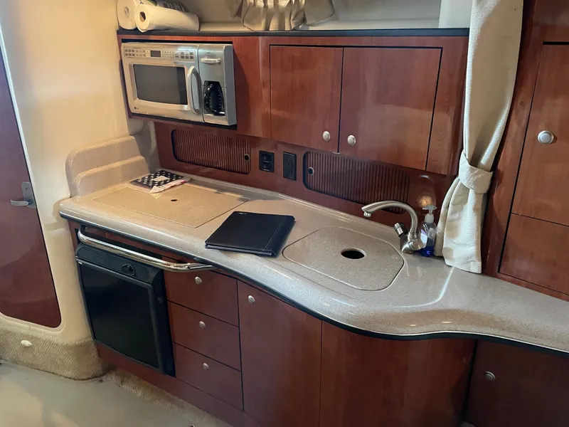 Slide: The Image of 2007 Sea Ray 320 Sundancer kitchen with microwave, sink, and wooden cabinetry. - 7