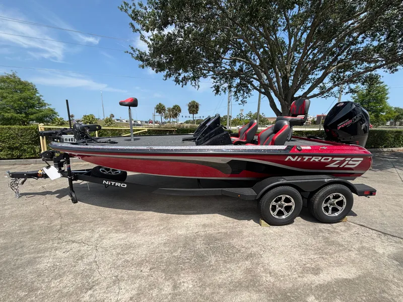 The Image of 2025 Nitro Z19 Pro boat on trailer, red and black design, parked outdoors. - 0