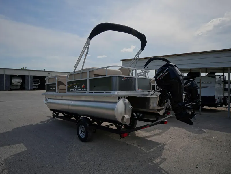 Slide: The Image of 2025 Sun Tracker Party Barge 18 DLX pontoon boat on trailer, parked outdoors. - 3