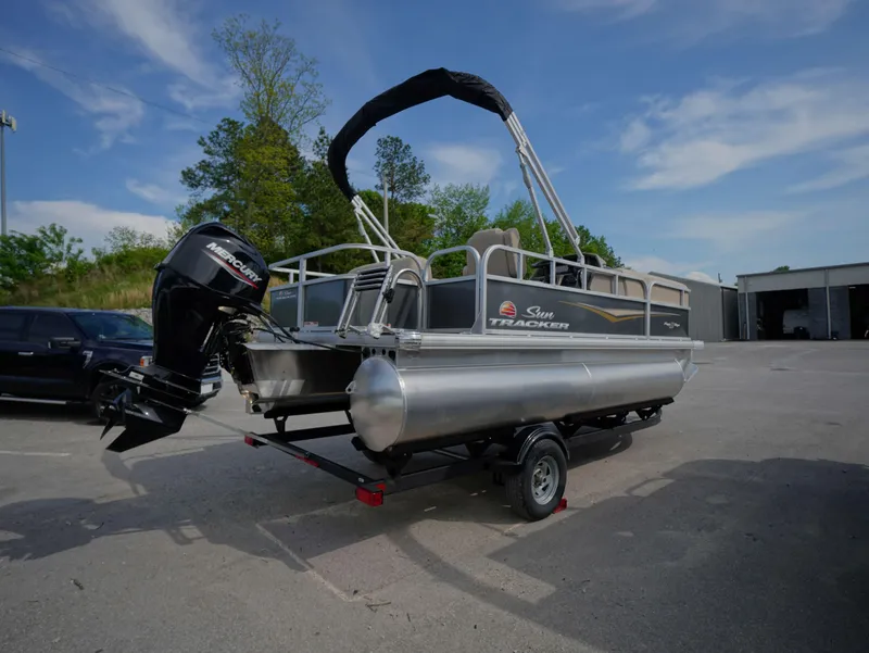 Slide: The Image of 2025 Sun Tracker Party Barge 18 DLX pontoon boat on trailer, outdoors. - 4