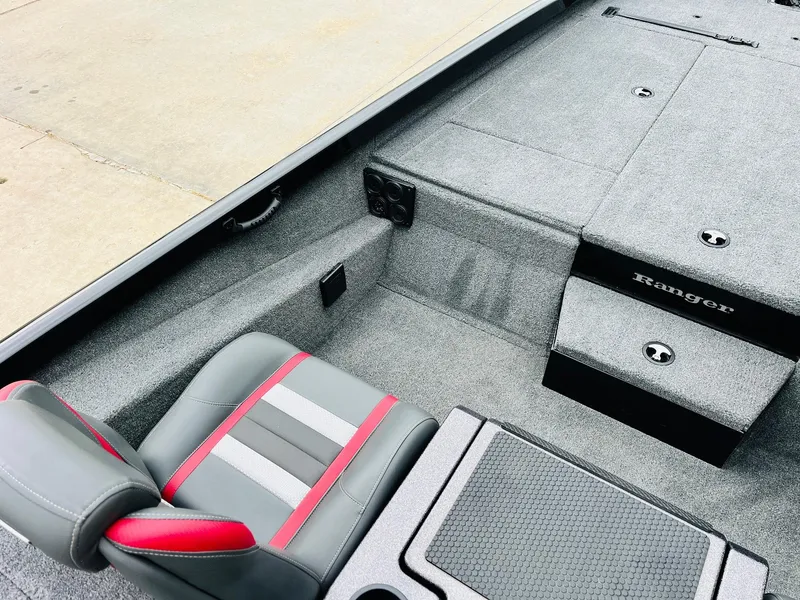 Slide: The Image of 2024 Ranger RT198P boat interior with gray and red seating, carpeted deck, and storage compartments. - 25