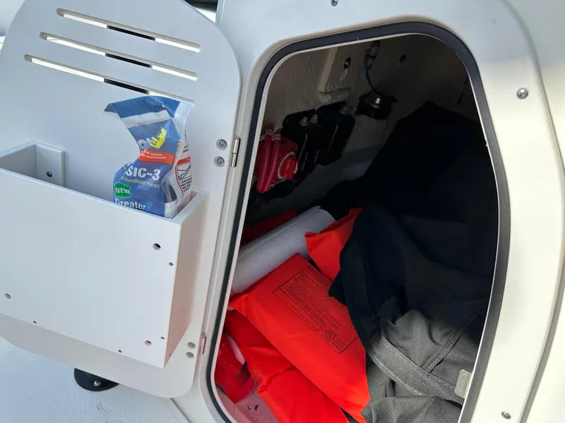 Slide: The Image of 2024 Boston Whaler 190 Montauk storage compartment with safety gear and accessories. - 11