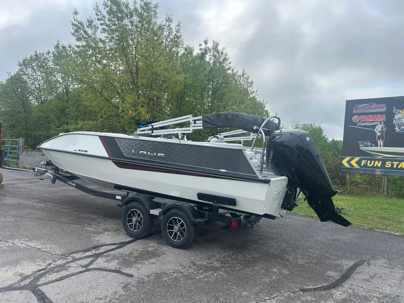 Slide: The Image of 2025 Lowe Deck SD224 boat on trailer, parked outdoors with trees in the background. - 1