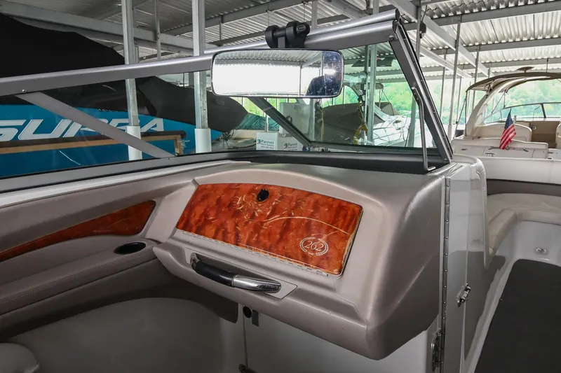 Slide: The Image of 2005 Cobalt 262 boat interior with wood accents and sleek design in a marina setting. - 23