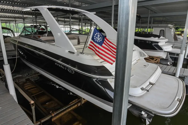 Slide: The Image of 2005 Cobalt 262 boat docked with American flag, under covered marina. - 3