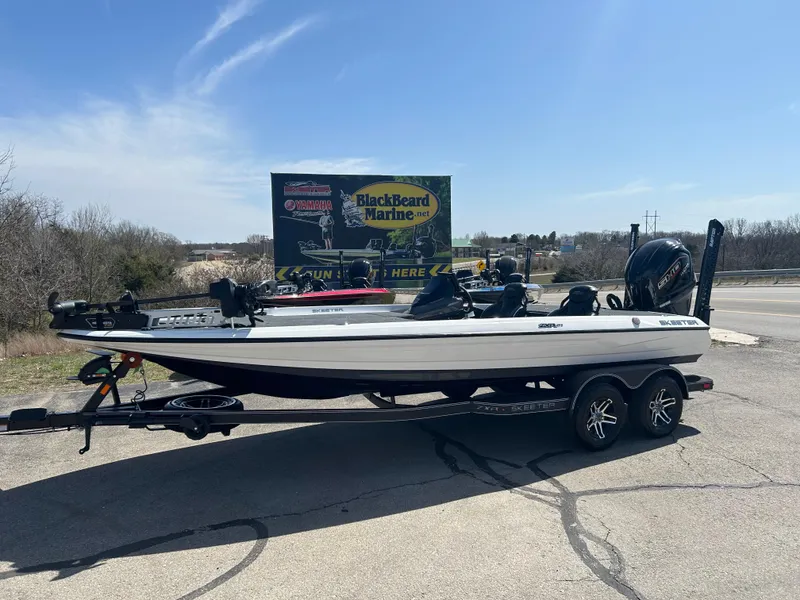 Slide: The Image of 2025 Skeeter ZXR21 boat on trailer, parked outdoors under clear blue sky. - 0