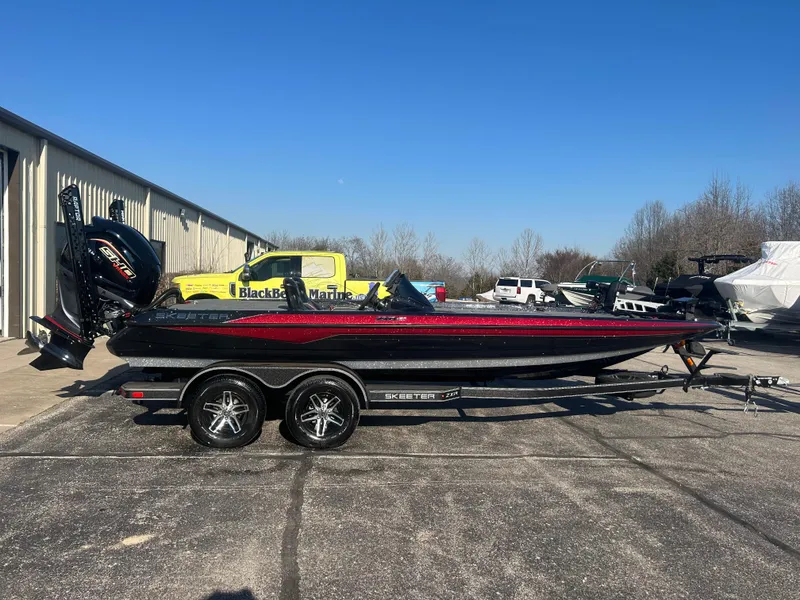 Slide: The Image of 2025 Skeeter ZXR21 boat on trailer, parked outdoors near a building. - 0