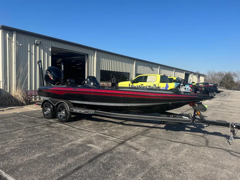Slide: The Image of 2025 Skeeter ZXR21 boat on trailer outside a warehouse, sunny day. - 1