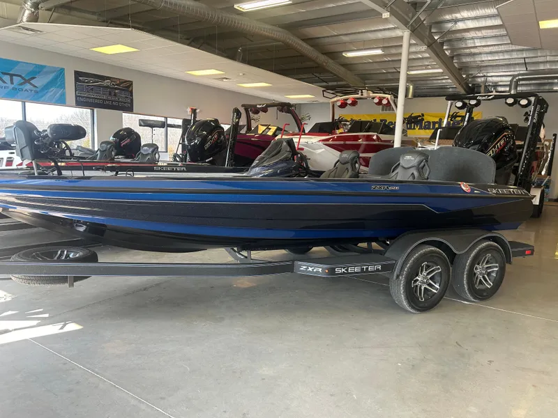 Slide: The Image of 2025 Skeeter ZXR20 boat in showroom, blue exterior, on trailer, indoor lighting. - 1
