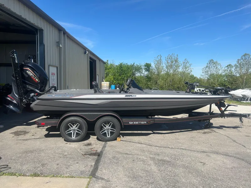 Slide: The Image of 2025 Skeeter ZXR20 boat on trailer outside a warehouse, sunny day. - 0