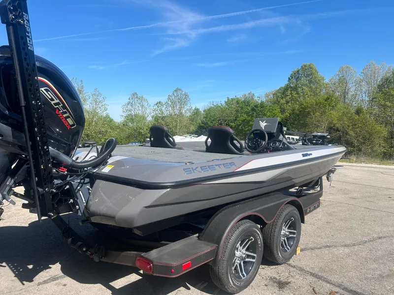 Slide: The Image of 2025 Skeeter ZXR20 boat on trailer, parked outdoors with trees in background. - 2