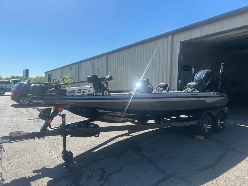 Slide: The Image of 2025 Skeeter ZXR20 bass boat parked outside a warehouse. - 3