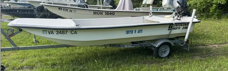 Slide: The Image of 2015 Carolina Skiff J16CC boat on trailer, parked on grass. - 1