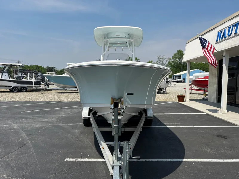 Slide: The Image of 2013 Sportsman 229 Heritage boat on trailer, parked outside a dealership with American flag. - 2