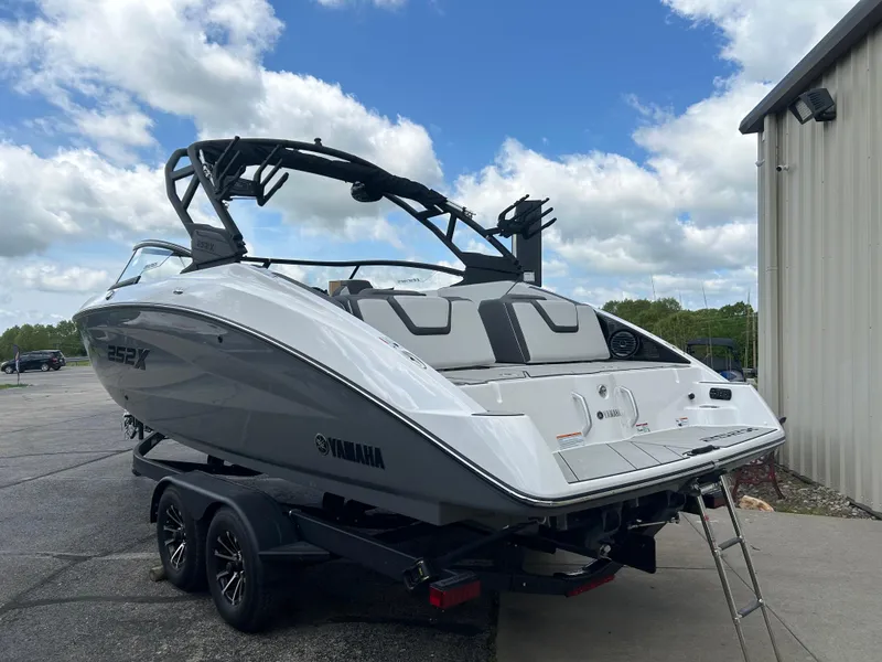 Slide: The Image of 2025 Yamaha Boats 252XE on trailer, sleek design, parked outdoors. - 2