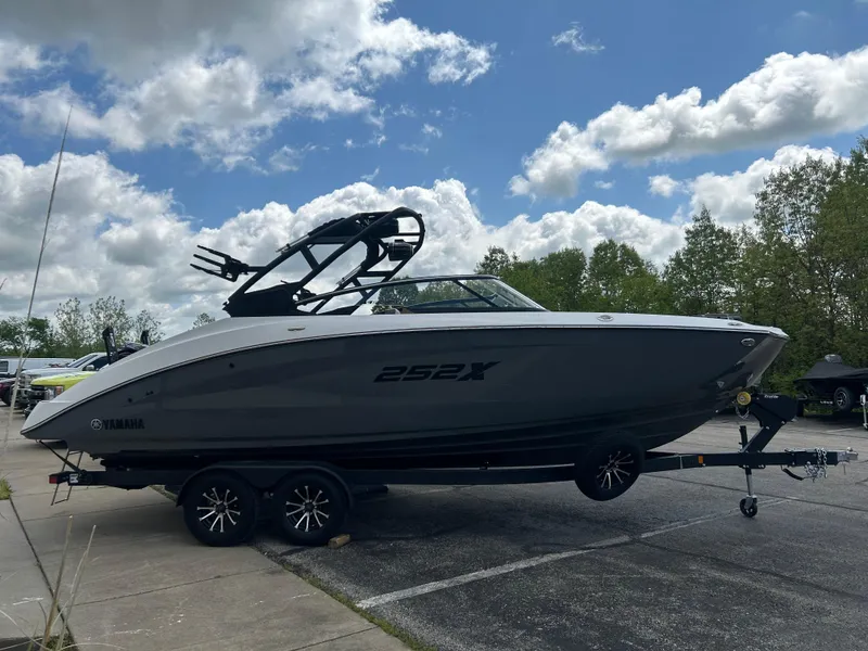 Slide: The Image of 2025 Yamaha Boats 252XE on trailer, parked outdoors under a partly cloudy sky. - 4