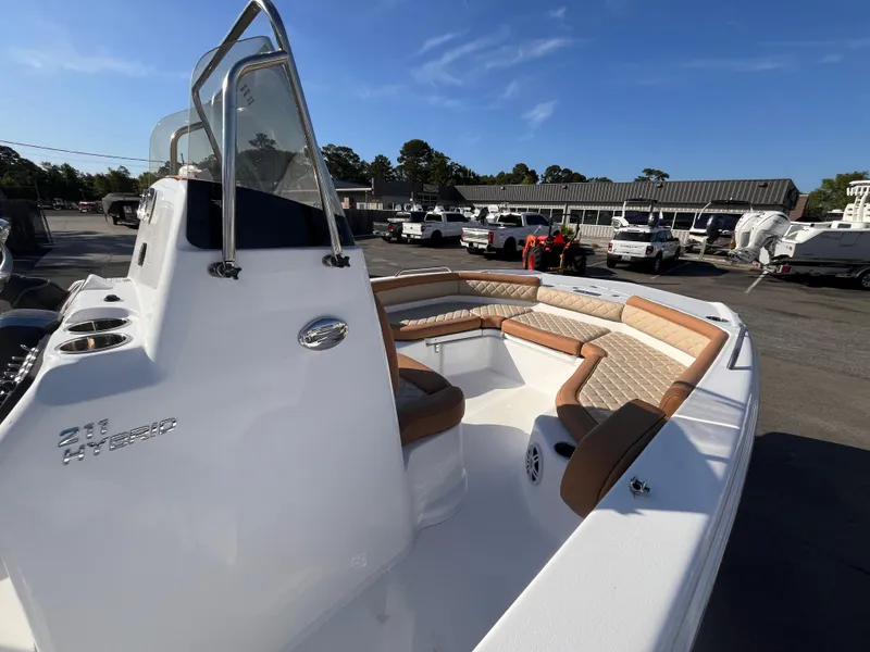 Slide: The Image of 2025 NauticStar 211 Hybrid boat with tan seating, docked under clear blue sky. - 6