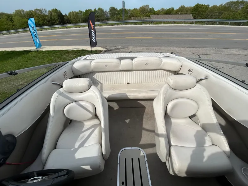 Slide: The Image of 2005 Crownline 180 BR boat interior with white seating, parked near a road. - 7