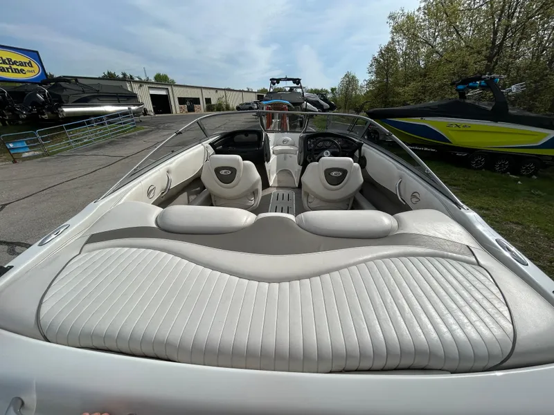 Slide: The Image of 2005 Crownline 180 BR boat with white interior, parked outdoors near other boats. - 9