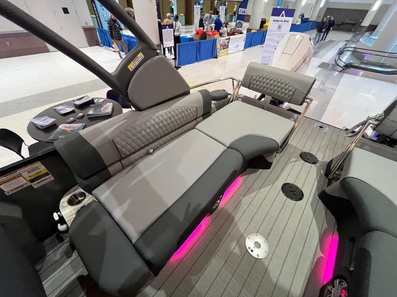 Slide: The Image of 2025 Avalon Excalibur LTD Quad Lounge boat interior with gray seating and pink LED lighting. - 27
