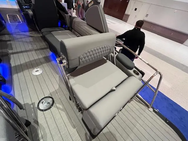 Slide: The Image of 2025 Avalon Excalibur LTD Quad Lounge boat interior with gray seating and blue accent lighting. - 35