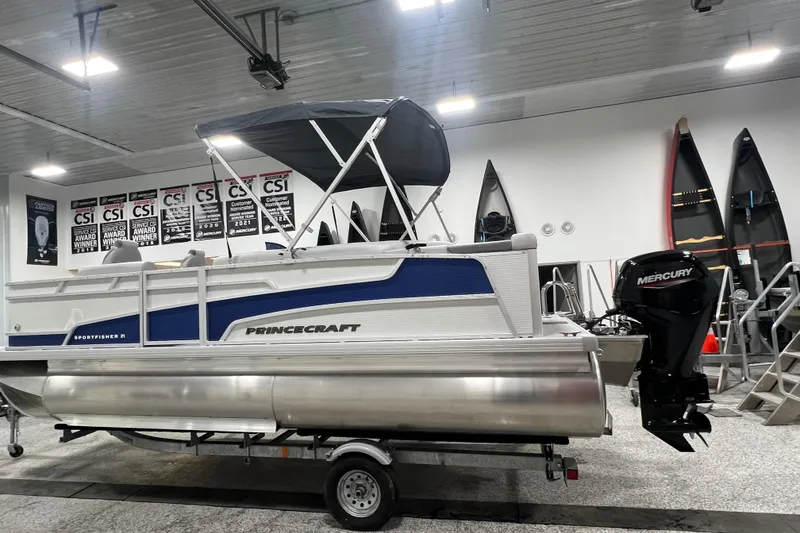 Slide: The Image of 2025 Princecraft Sportfisher 21-2S pontoon boat in showroom with Mercury outboard motor. - 12